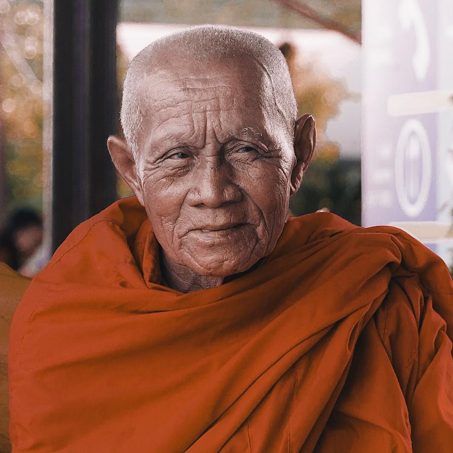 monk wearing orange shirt sitting on bench